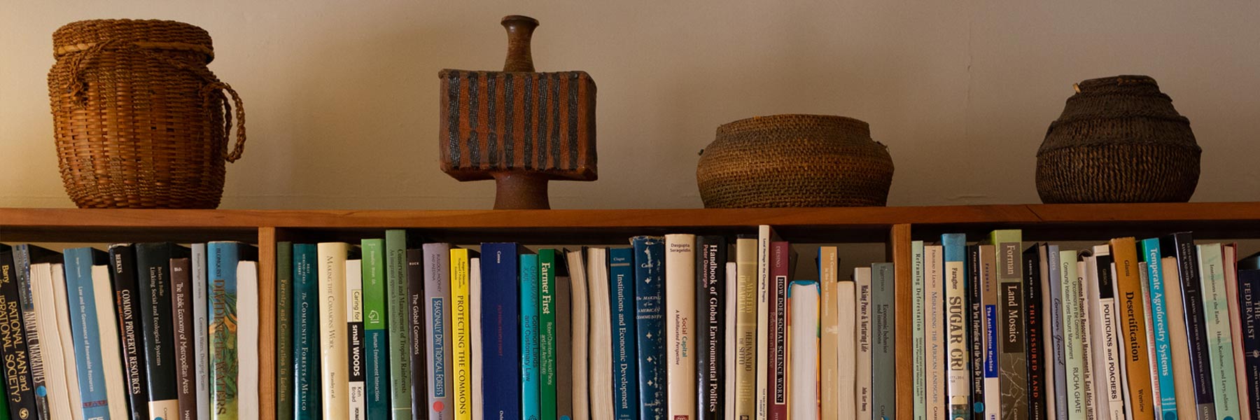 A line of differently-shaped woven baskets on top of a bookshelf at the Ostrom Workshop. 