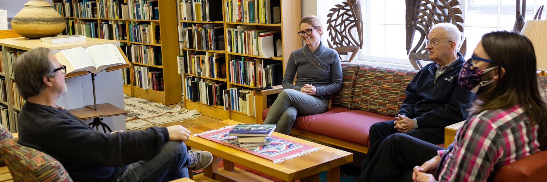 Four people have a comfortable discussion in the Ostrom Workshop's library. 