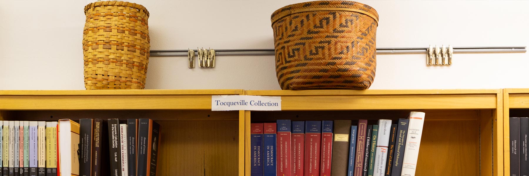 A line of decorative baskets above a full bookshelf labeled Tocqueville Collection. 